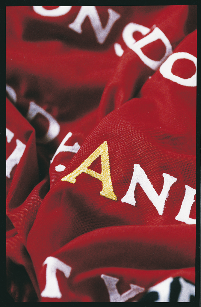 Detail of embroidered lettering on a red poetry flag